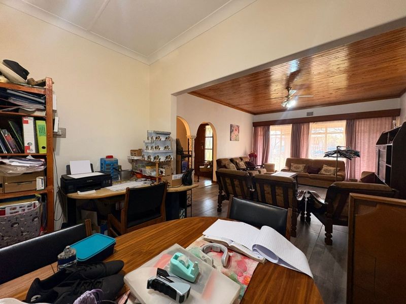 Open plan living area featuring a timber ceiling, ceiling fan, and tiled flooring, connecting to an adjacent room through a classic archway.