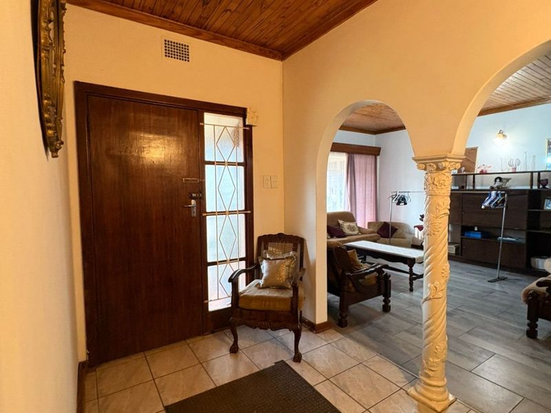 Welcoming entrance hall featuring a solid timber front door, decorative arched column, and warm timber-clad ceiling, leading into the open-plan living area.