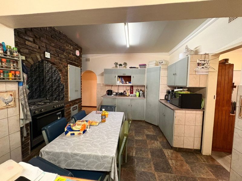 A functional kitchen featuring a distinctive brick feature wall, built-in oven, and ample cabinetry, offering a traditional layout with potential for modern updates.