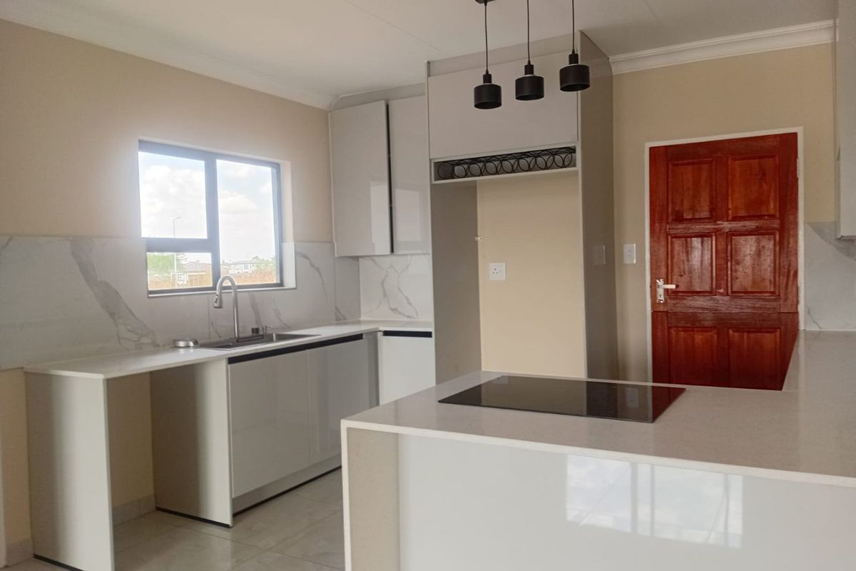Modern kitchen featuring sleek cabinetry, quartz countertops, marble-look splashback, integrated electric hob, and contemporary pendant lighting in a clean, open-plan layout.