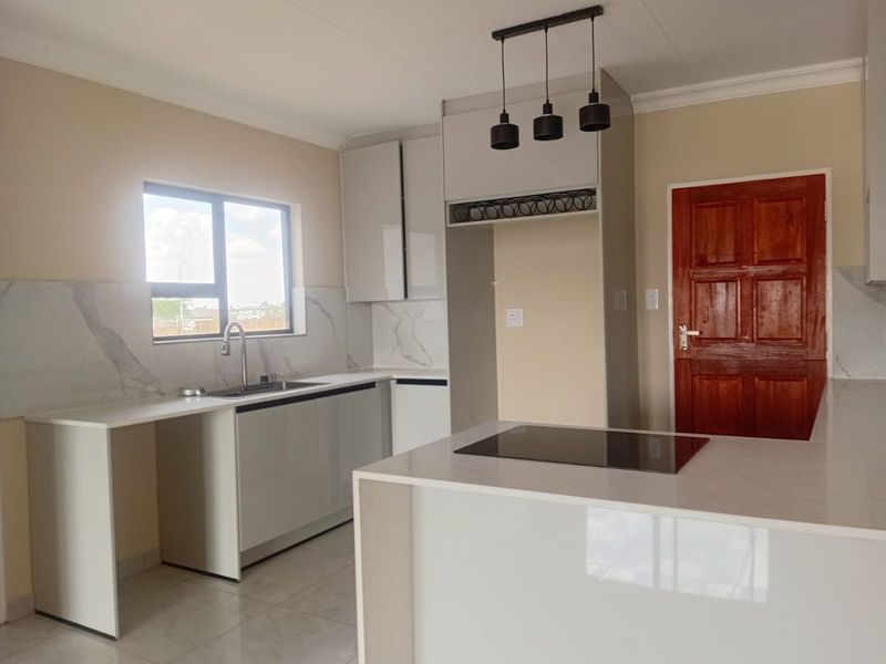 Modern kitchen featuring sleek cabinetry, quartz countertops, marble-look splashback, integrated electric hob, and contemporary pendant lighting in a clean, open-plan layout.