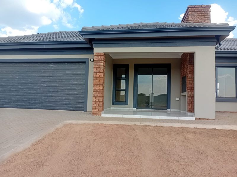 Modern single-story home featuring a double garage, brick accents, tiled roof, and a covered entrance with a built-in braai area.