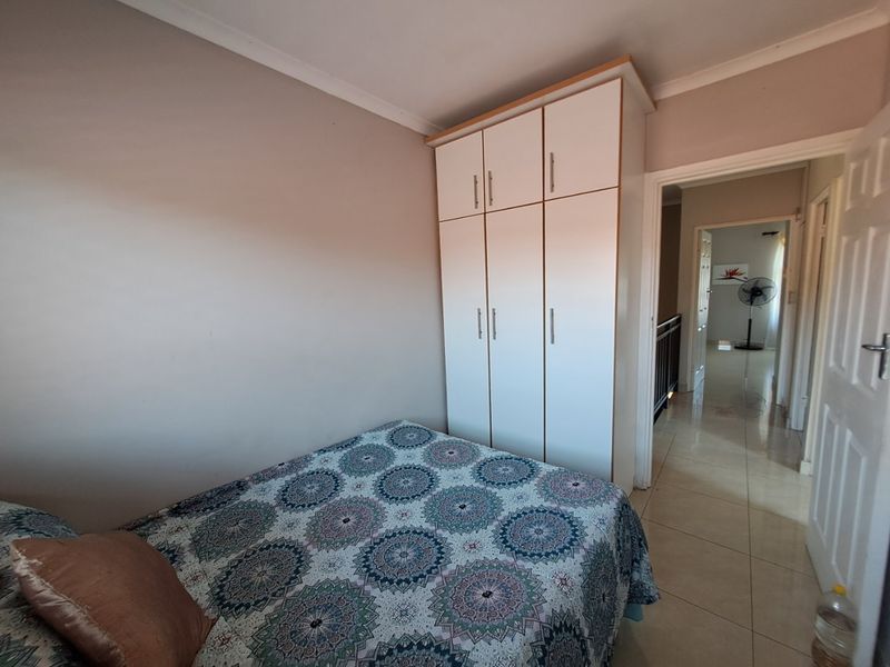 A bedroom featuring a built-in wardrobe, tiled flooring, and coved ceiling, with a view leading into the hallway.