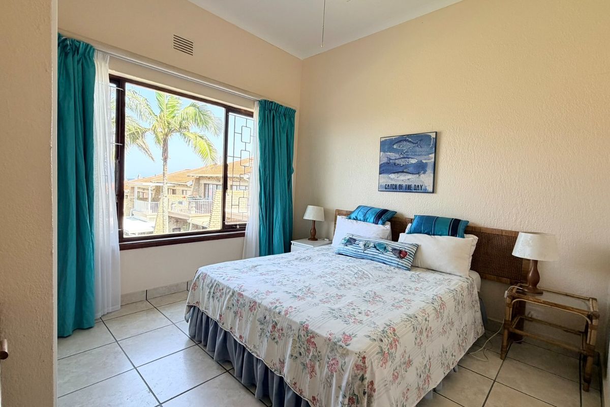 A well-lit bedroom featuring tiled flooring and a large window with views, providing a comfortable and functional living space.