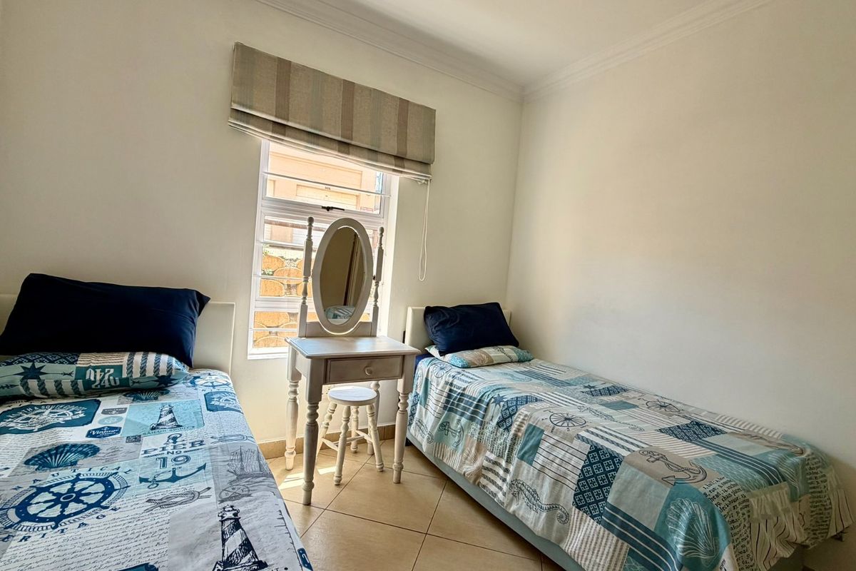 A functional bedroom featuring tiled flooring, a window with a fitted roman blind, and decorative ceiling cornicing.