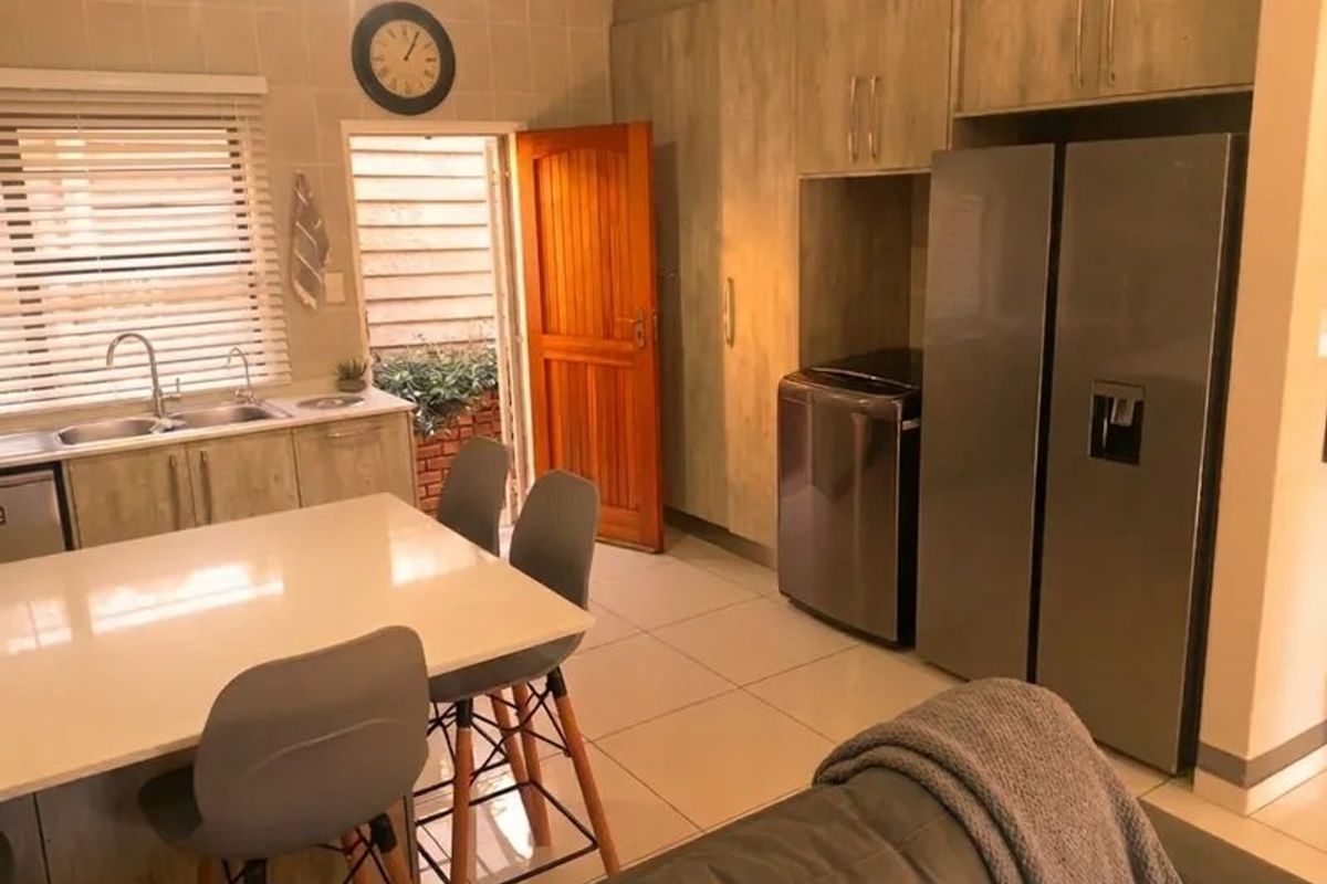 A functional kitchen featuring built-in cabinetry, a double sink, and tiled flooring, with direct access to an outdoor area.