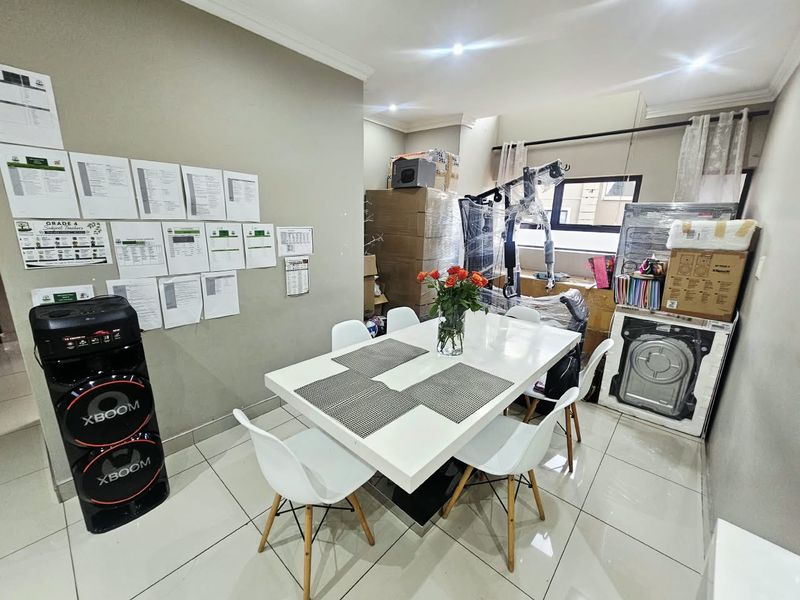 A dining area featuring tiled flooring and recessed downlighting, currently utilized as a multi-purpose space.