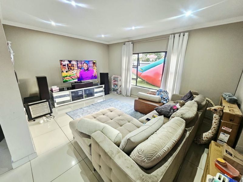 A comfortable living room featuring tiled flooring, recessed downlighting, and a large window providing natural light.