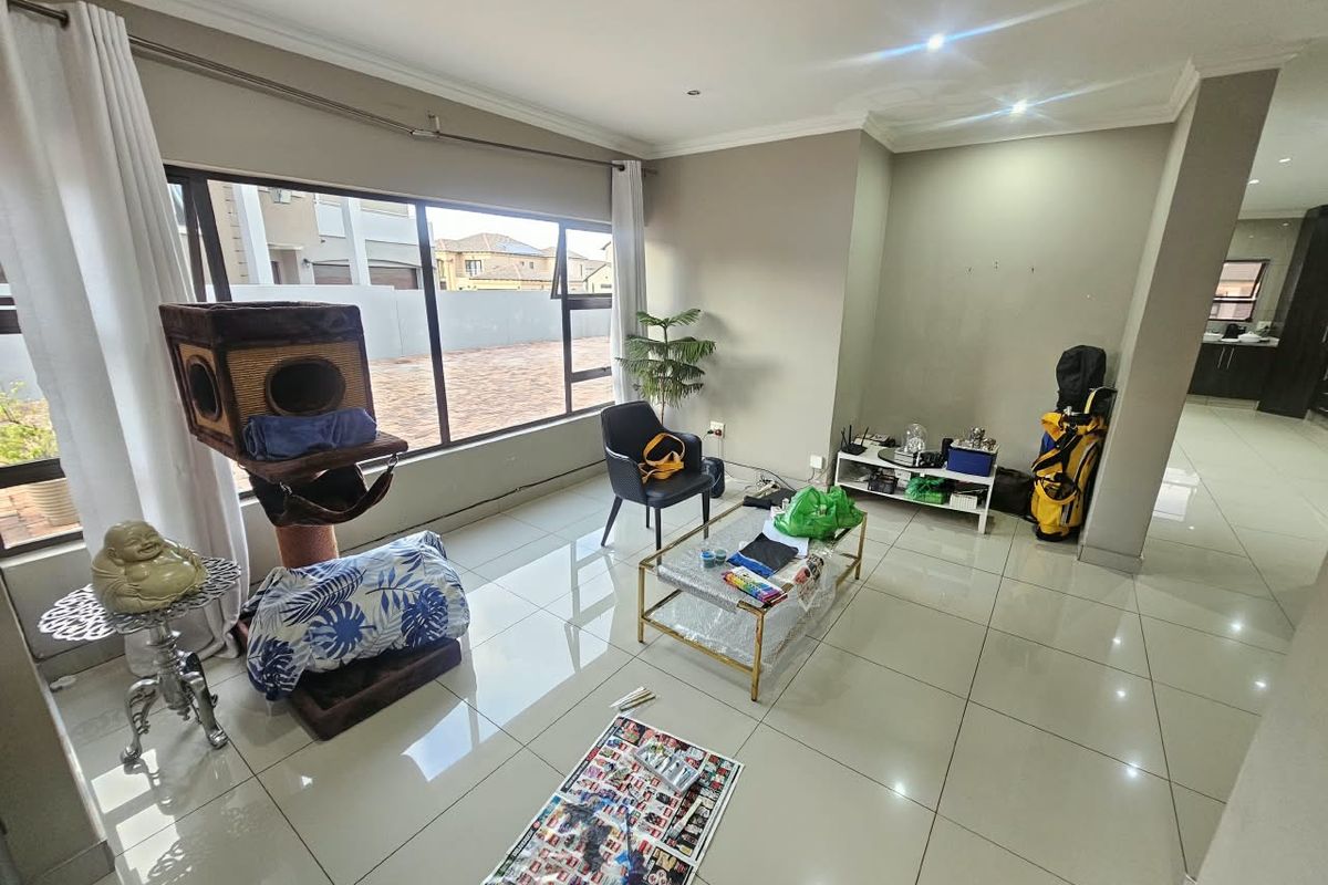 A bright living room featuring large windows, polished porcelain floor tiles, and recessed downlighting, offering a clean and neutral foundation for modern living.