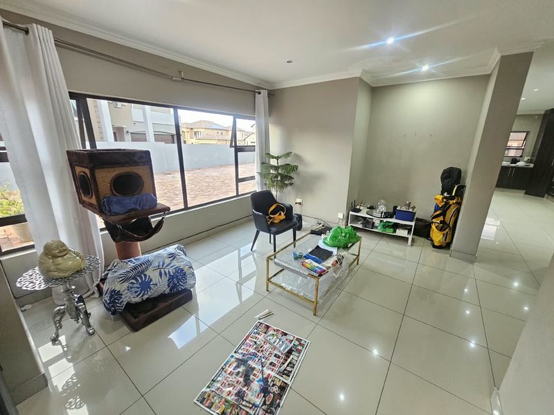 A bright living room featuring large windows, polished porcelain floor tiles, and recessed downlighting, offering a clean and neutral foundation for modern living.