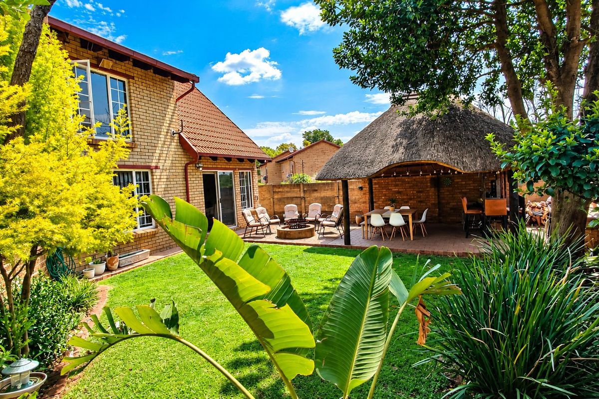 A well-maintained rear garden featuring a spacious thatched lapa, brick paving, and established landscaping, providing an ideal outdoor entertainment area.