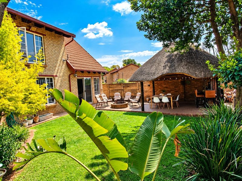 A well-maintained rear garden featuring a spacious thatched lapa, brick paving, and established landscaping, providing an ideal outdoor entertainment area.