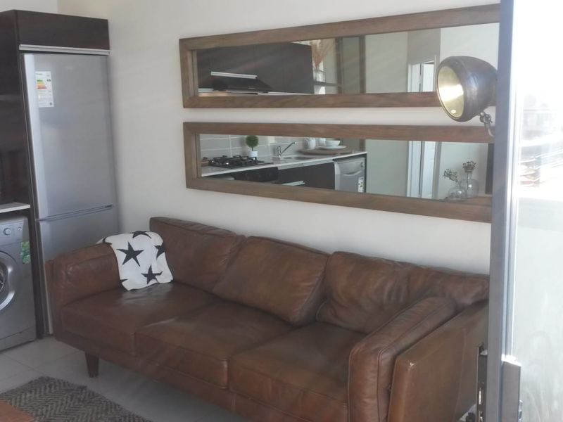 Compact open-plan living area featuring a modern kitchen with built-in cabinetry and tiled flooring, seamlessly integrated with the lounge space.