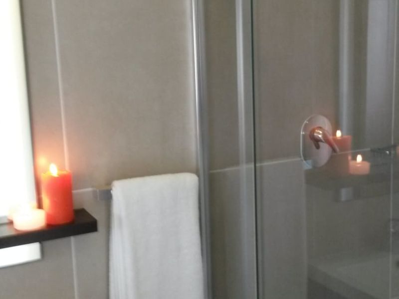A modern bathroom featuring a glass-enclosed shower, vanity basin, and neutral wall tiling.