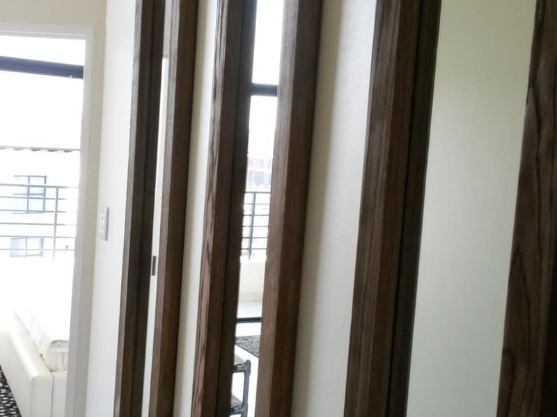 A bright hallway featuring tiled flooring and decorative full-length recessed wall mirrors, leading towards an adjacent living space.