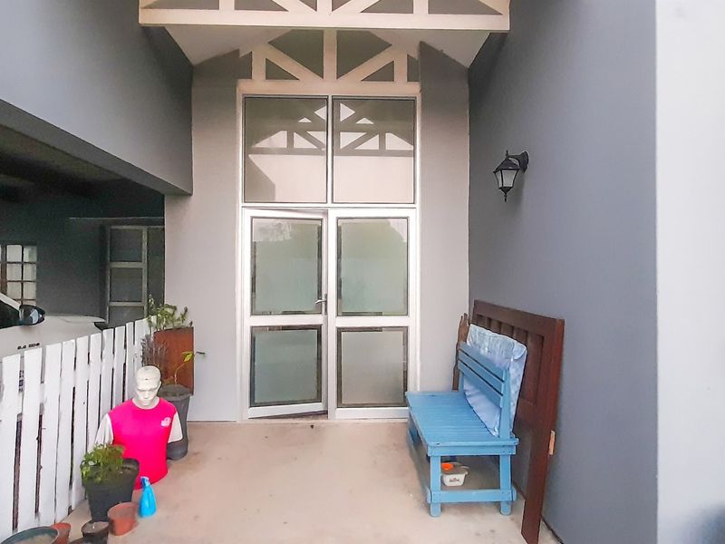 Covered entrance area featuring a double glass door with transom window and exterior wall lighting.