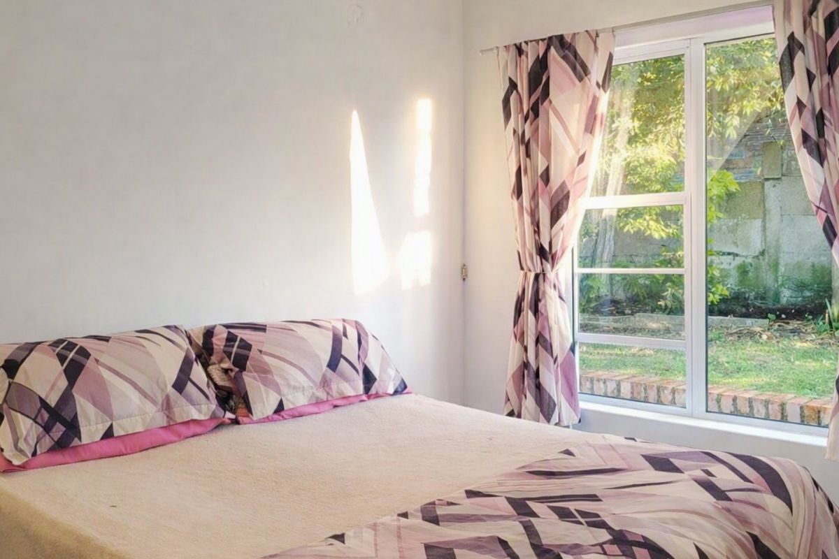 A bright bedroom featuring a large window with garden views, providing natural light and a comfortable atmosphere.