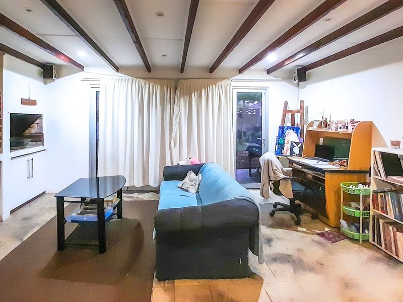 Spacious living area featuring exposed timber ceiling beams, built-in cabinetry, a fireplace, and direct access to the outdoor area through sliding glass doors.