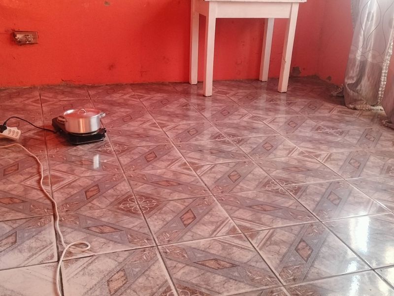 An empty living area featuring patterned ceramic floor tiles and bright orange wall paint, offering a blank canvas for potential interior updates.