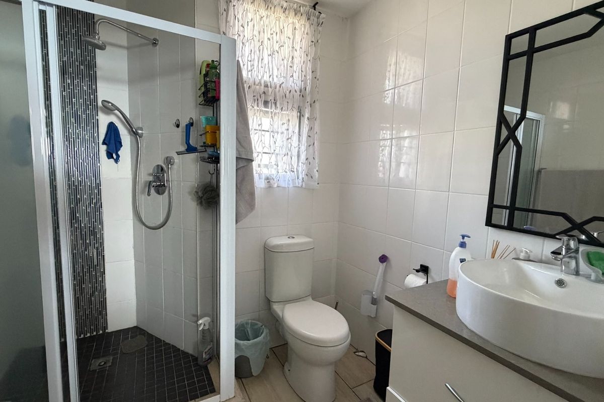 A functional bathroom featuring a glass-enclosed shower, a modern vessel sink vanity, and neutral wall tiling.