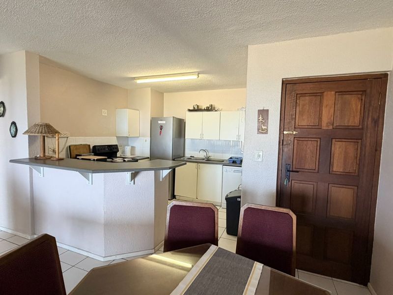 Open-plan kitchen and dining area featuring a breakfast bar, tiled flooring, and functional cabinetry, offering a practical layout for daily living.