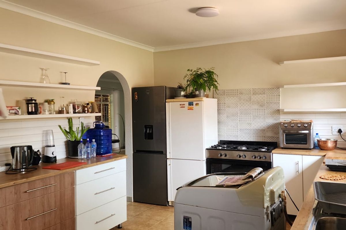 A functional kitchen featuring wood-look cabinetry, open shelving, a gas stove, and a tiled backsplash, providing a practical workspace for daily cooking.