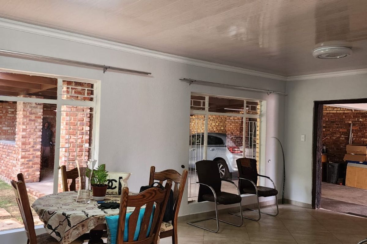 Spacious living area featuring tiled flooring, large windows providing natural light, and views of the outdoor patio and garden area.
