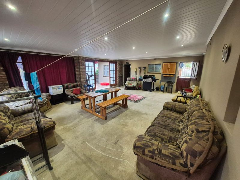 Spacious covered patio area featuring exposed brick walls, recessed lighting, and direct access to the garden through French doors.