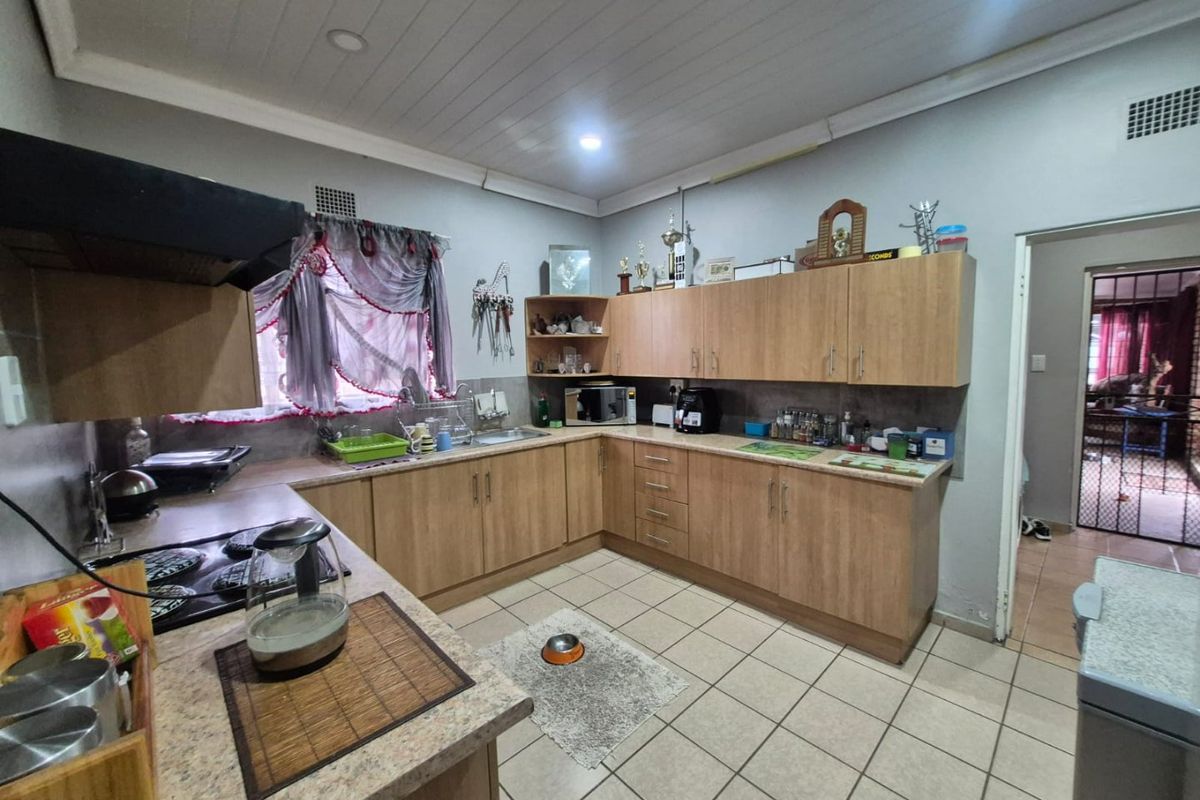 Functional kitchen featuring laminate cabinetry, ample counter space, built-in hob with extractor fan, and tiled flooring.