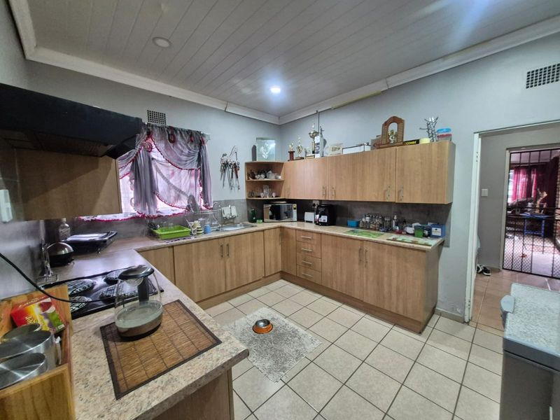 Functional kitchen featuring laminate cabinetry, ample counter space, built-in hob with extractor fan, and tiled flooring.