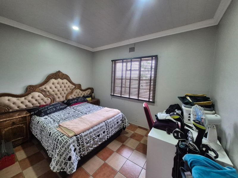 A bedroom featuring tiled flooring, recessed ceiling lighting, and venetian blinds, providing a functional space with neutral wall tones.