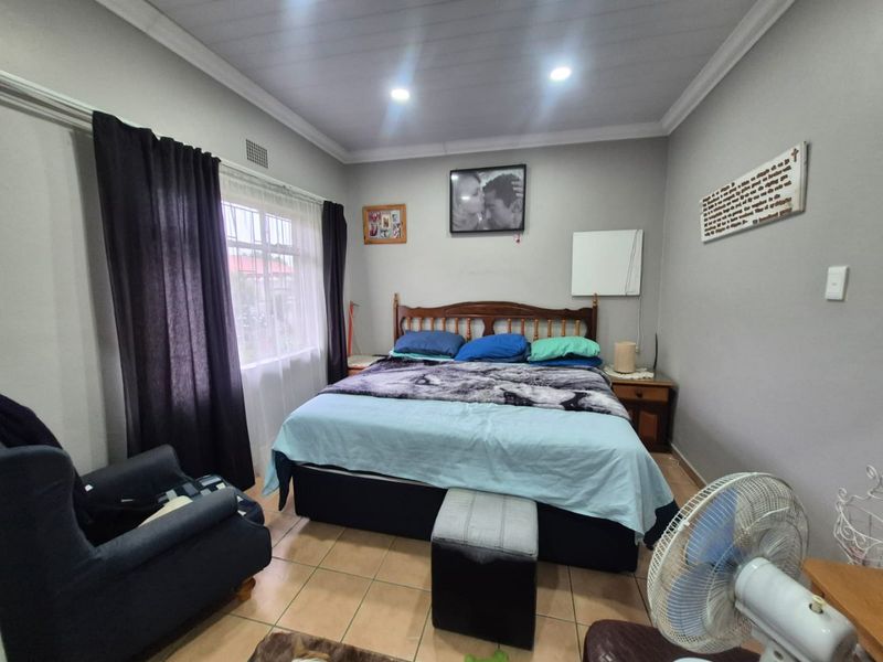 A functional bedroom featuring tiled flooring, recessed downlighting, and a coved ceiling, providing a comfortable and well-lit sleeping space.