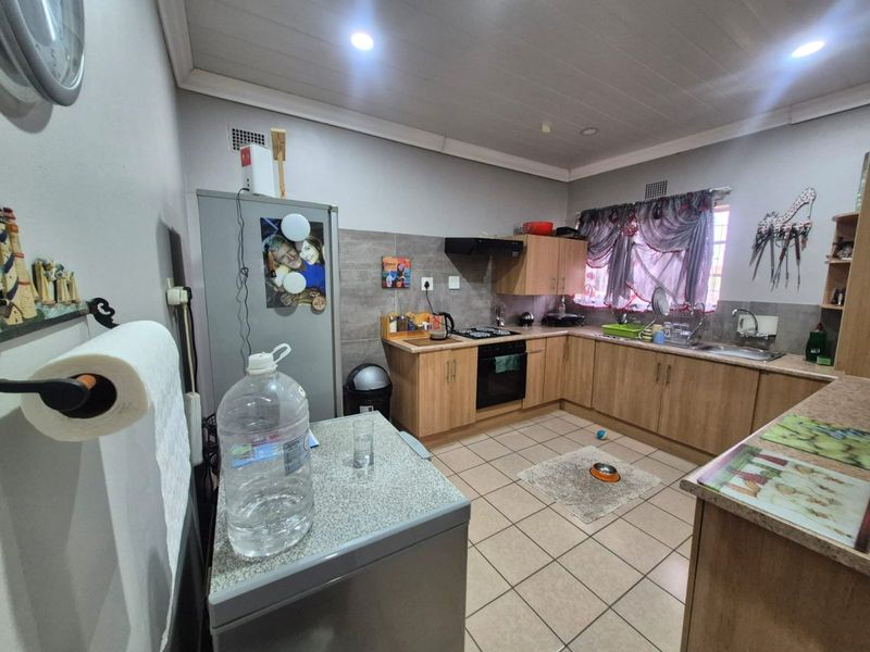 A functional kitchen featuring wood-look cabinetry, laminate countertops, built-in oven with hob, and tiled flooring, offering a practical layout for daily meal preparation.