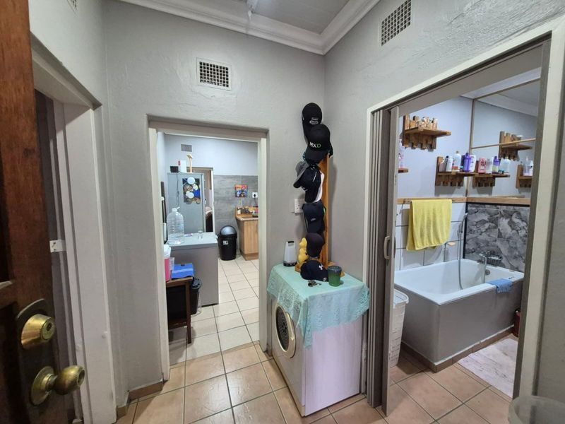 A functional hallway area providing access to a bathroom and a secondary utility or kitchen space, featuring tiled flooring and neutral wall finishes.