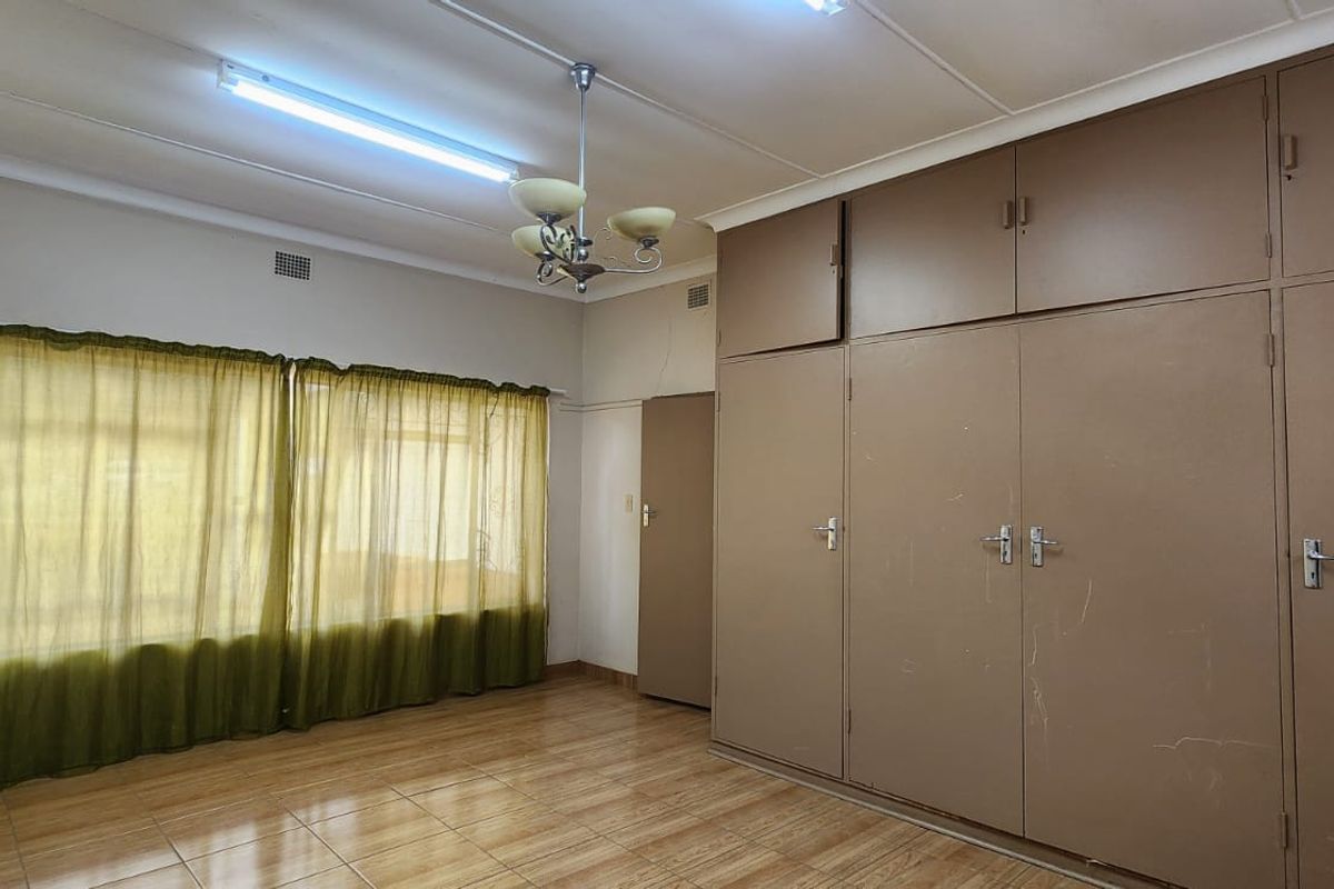 A spacious bedroom featuring tiled flooring and extensive built-in cupboards, offering a blank canvas for modern updates and interior design improvements.