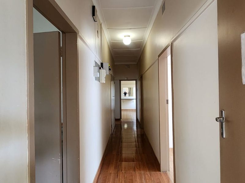 A functional hallway featuring tiled flooring and access to multiple rooms, showing signs of wear and requiring cosmetic updates.