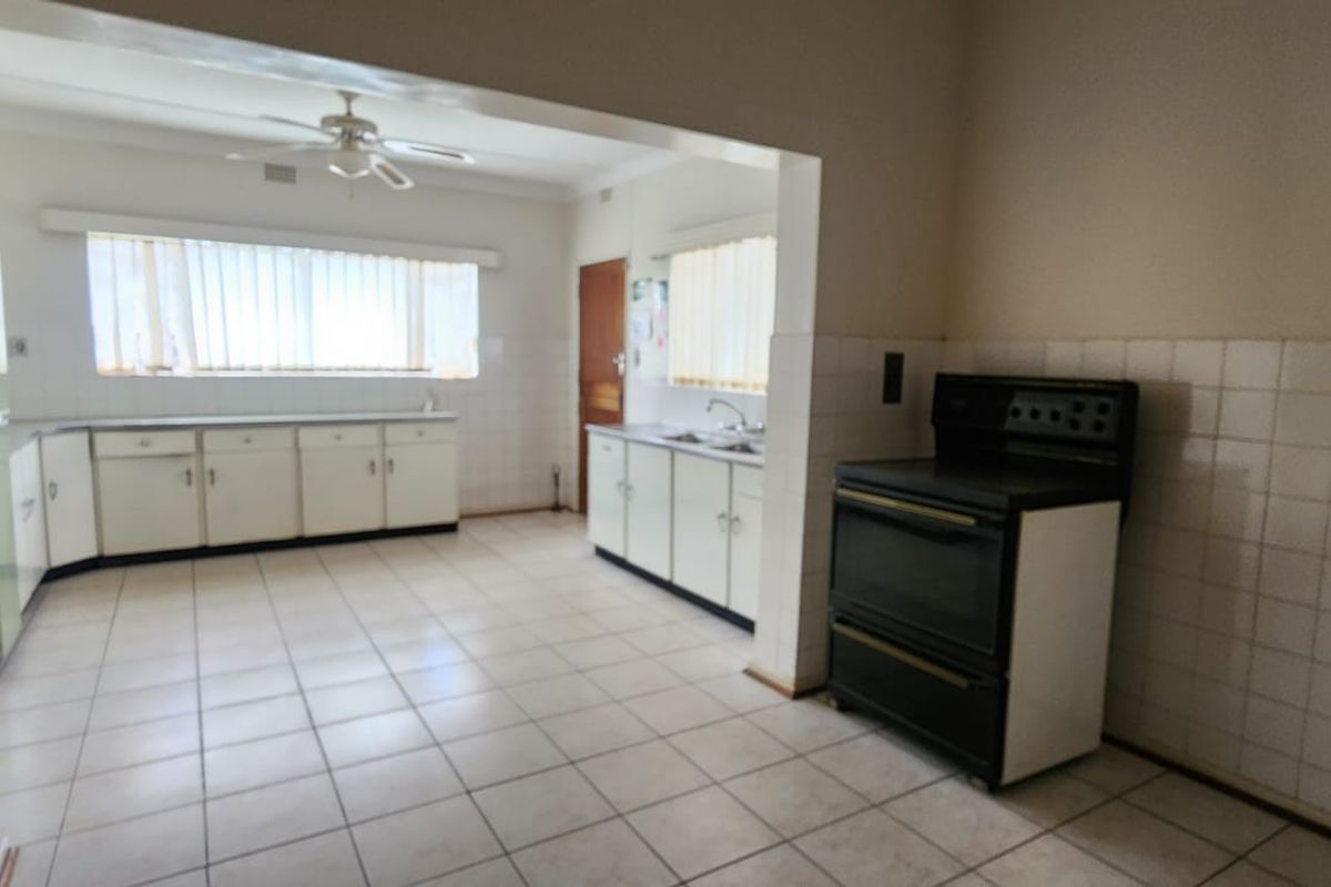 Spacious kitchen featuring tiled flooring, built-in cabinetry, a double sink, and a freestanding stove, offering a functional layout ready for modernization.