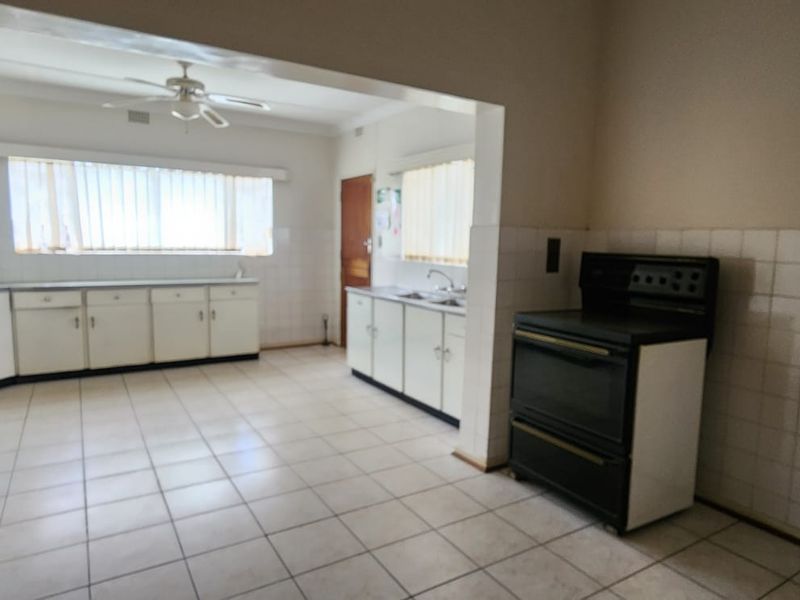 Spacious kitchen featuring tiled flooring, built-in cabinetry, a double sink, and a freestanding stove, offering a functional layout ready for modernization.