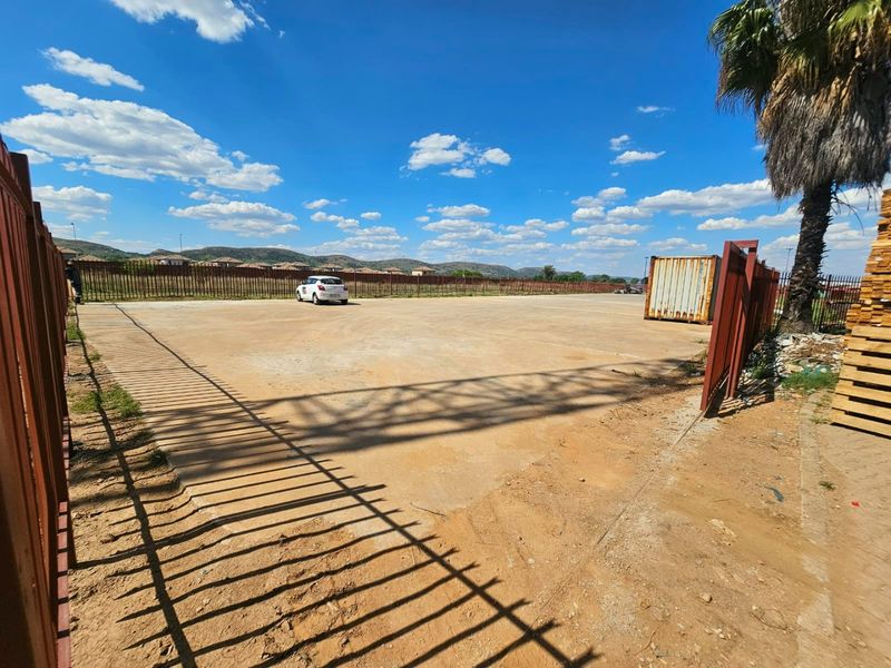 A spacious, level vacant residential stand featuring concrete paving, secure metal perimeter fencing, and a gated entrance.