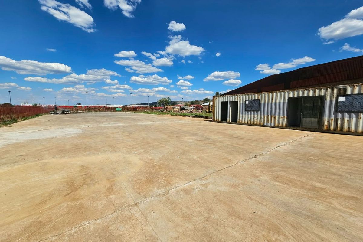 Expansive concrete yard featuring a repurposed shipping container structure, suitable for industrial or commercial storage use.