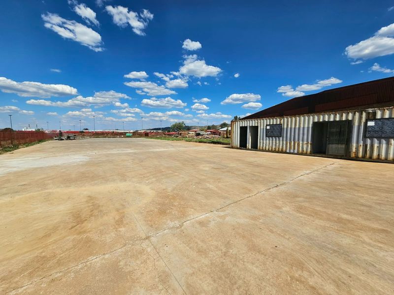 Expansive concrete yard featuring a repurposed shipping container structure, suitable for industrial or commercial storage use.