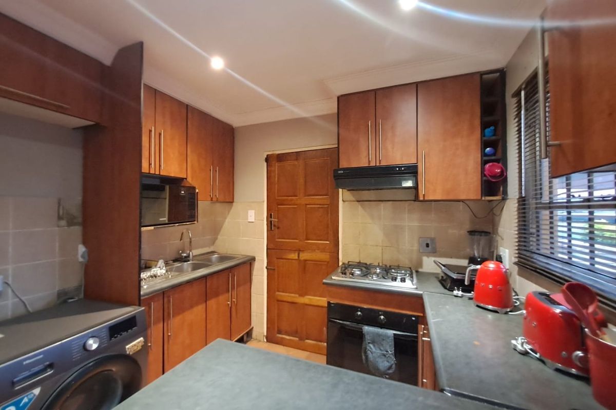 A functional kitchen featuring wooden cabinetry, built-in oven with gas hob, extractor fan, and tiled backsplash, providing a practical workspace.