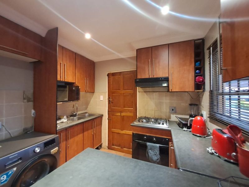 A functional kitchen featuring wooden cabinetry, built-in oven with gas hob, extractor fan, and tiled backsplash, providing a practical workspace.