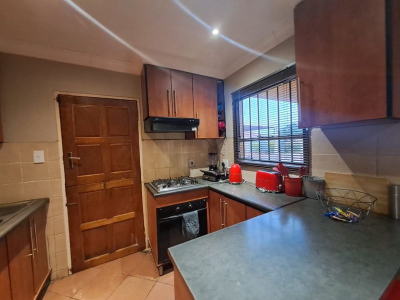 Functional kitchen featuring built-in wooden cabinetry, gas hob, oven, extractor fan, and tiled backsplash with ample countertop workspace.