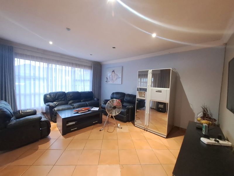 Spacious living room featuring tiled flooring and recessed downlighting, offering a functional layout with large windows for natural light.
