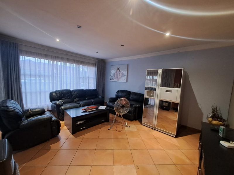 Spacious living room featuring tiled flooring and recessed downlighting, offering a comfortable area for relaxation and entertainment.