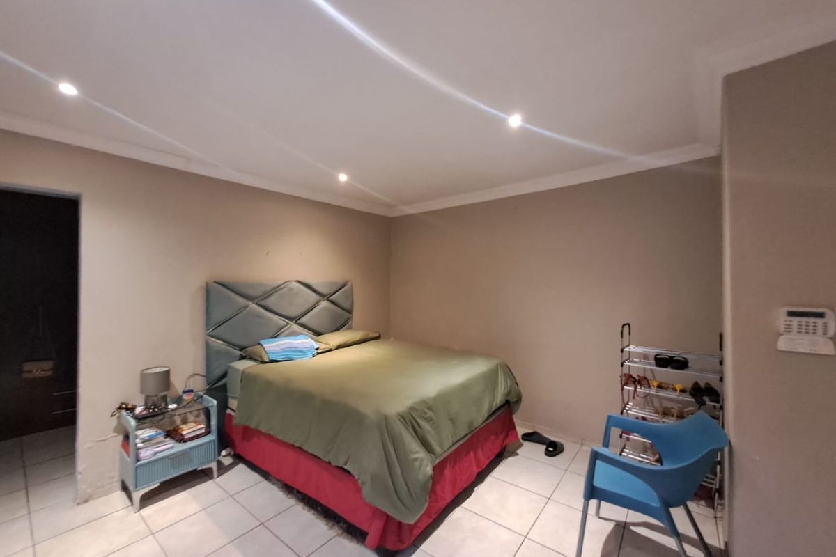 A bedroom featuring tiled flooring, recessed downlighting, and a wall-mounted alarm keypad.