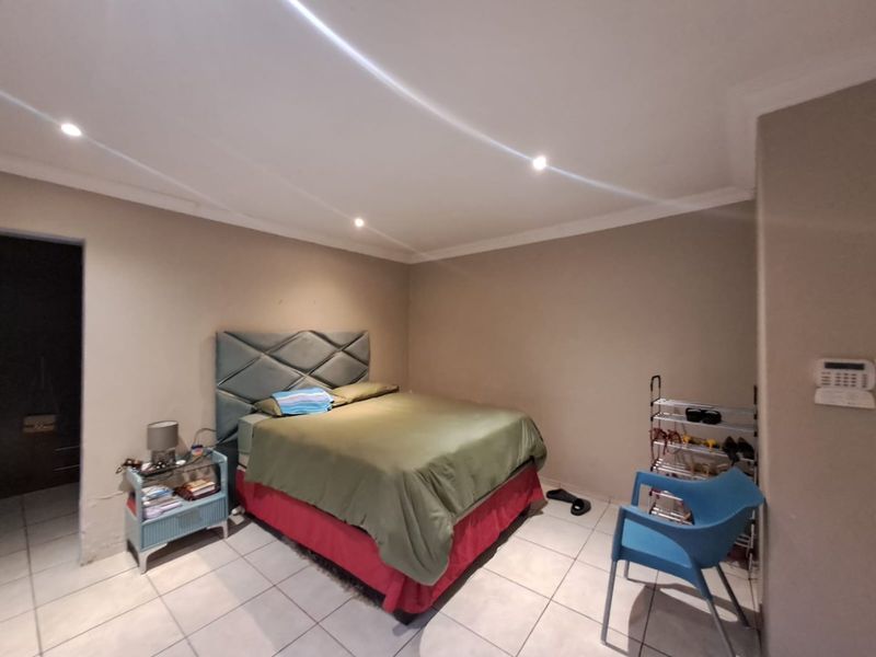 A bedroom featuring tiled flooring, recessed downlighting, and a wall-mounted alarm keypad.