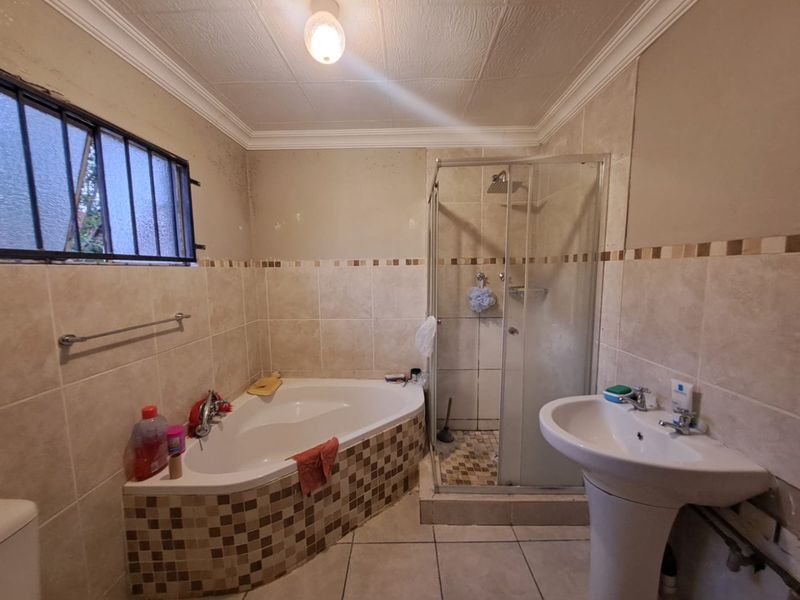 A dated bathroom featuring a corner bathtub, separate glass shower enclosure, and pedestal basin with tiled finishes throughout.