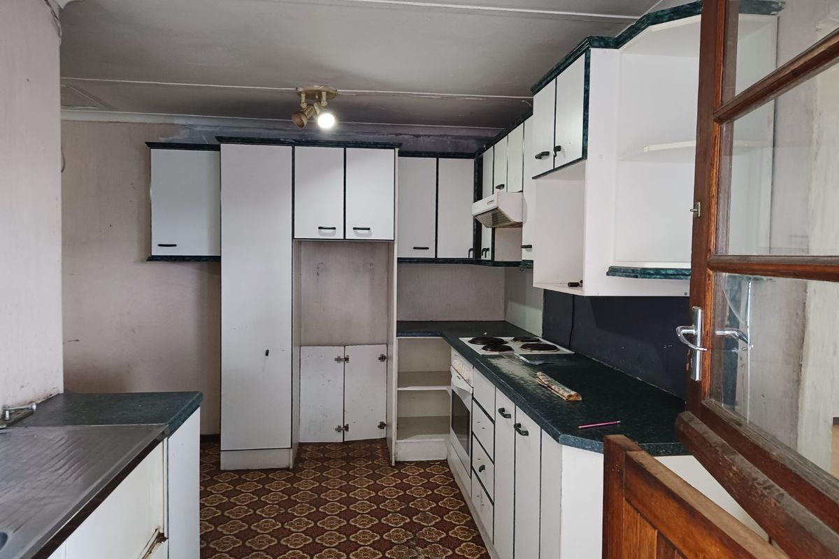 A dated kitchen featuring built-in cabinetry, an electric hob, and an oven, requiring significant renovation and modernization to reach its full potential.